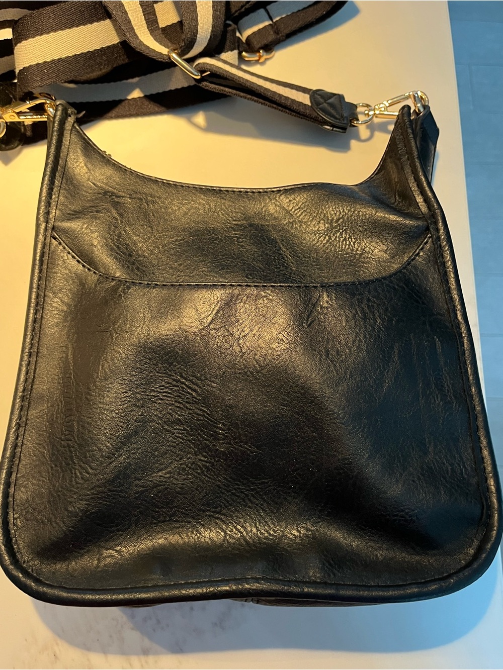 ah-dorned black vegan leather messenger bag w/guitar strap. Gold tone hardware